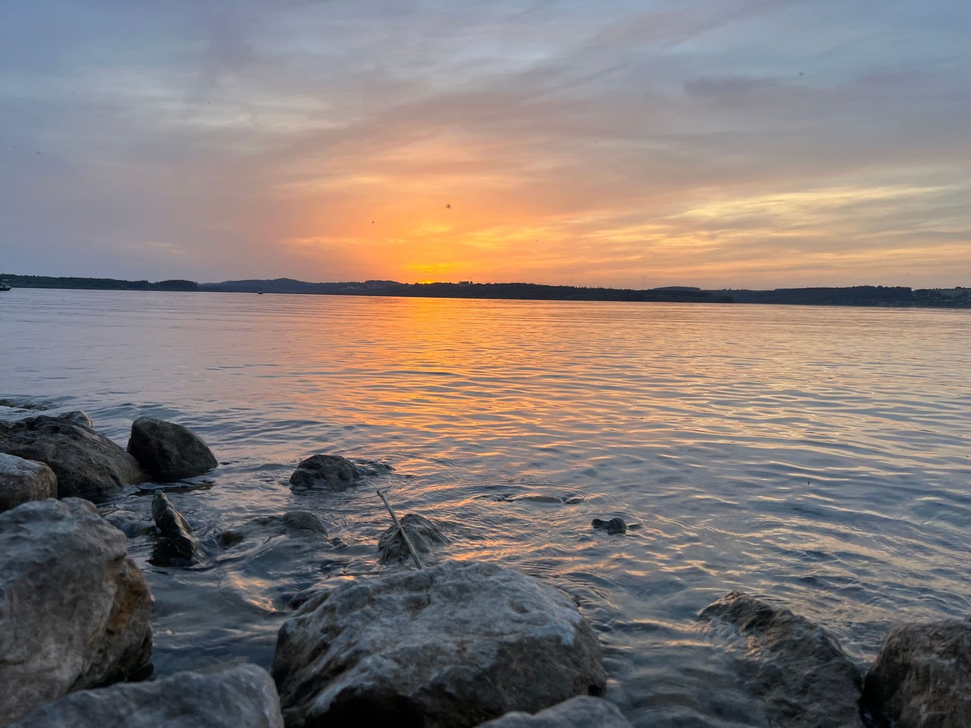 Sunset over the Brombachsee seen from rocks at the water's edge