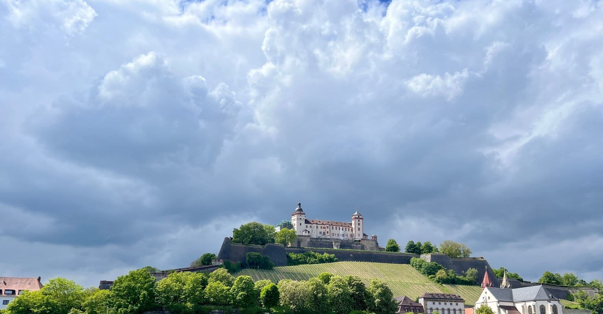 Marienberg Fortress above its vineyards under a dramatic cloudy sky