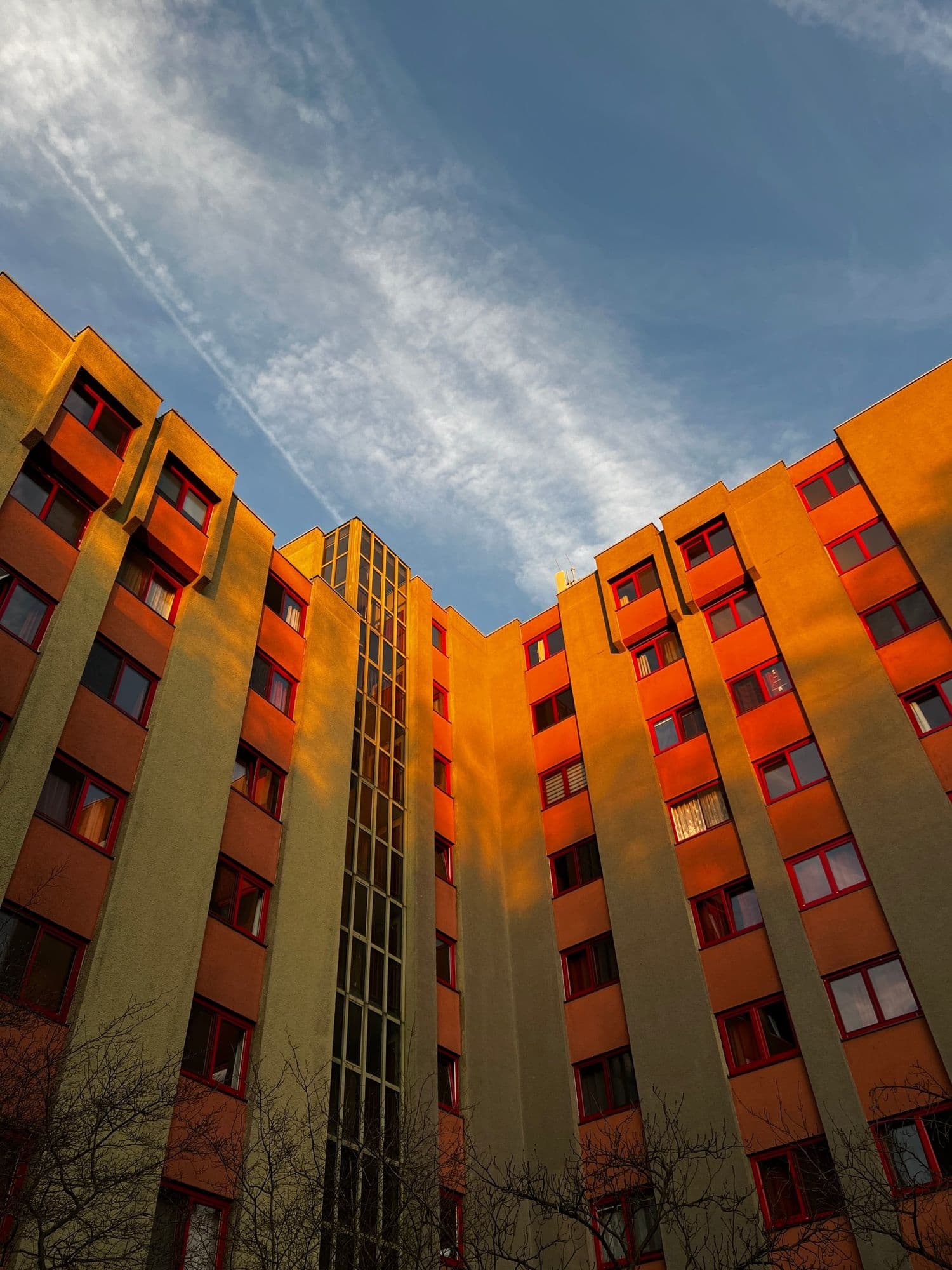 Orange apartment block glowing in the evening sun, seen from below