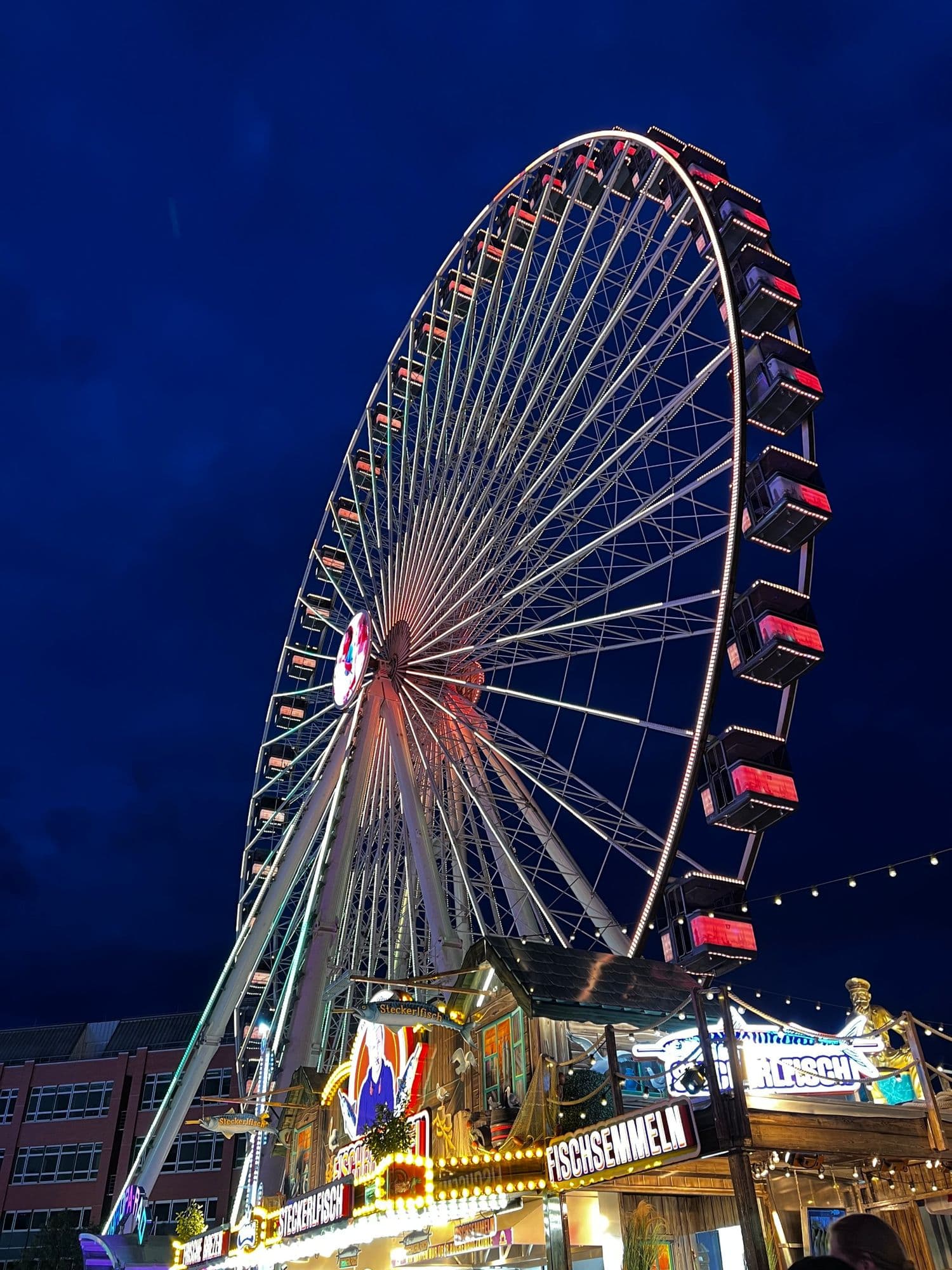 Lit-up Ferris wheel at a funfair against a deep blue night sky